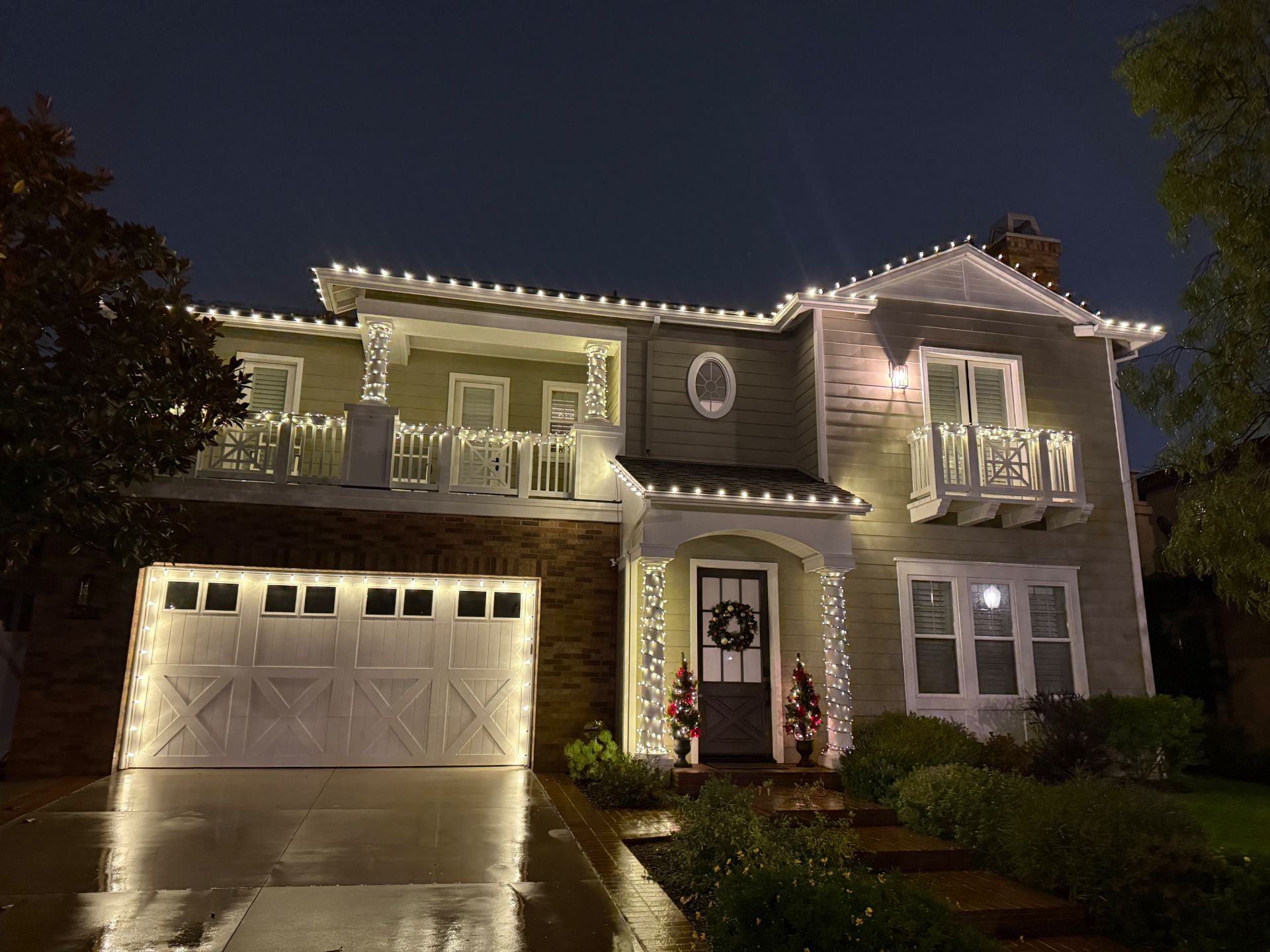 Custom warm-white roofline and entry lighting on a two-story Christmas estate