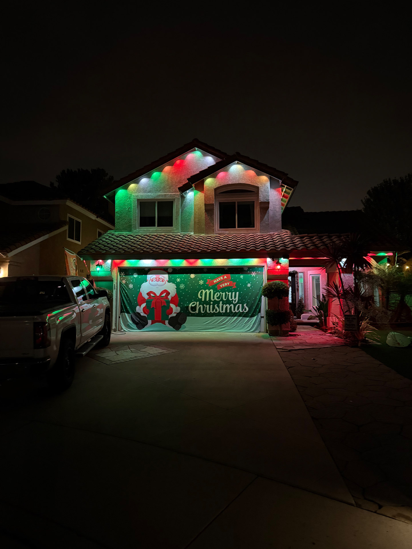 Red and green Christmas roofline lighting and colorful Santa display on a home